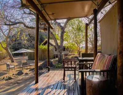 a porch with chairs and a table and a picnic table at Abelana Safari Camp in Phalaborwa