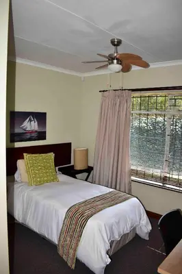 a bedroom with a bed with a ceiling fan and a window at 13 Hobson in Secunda