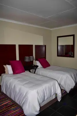two beds in a hotel room with pink pillows at 13 Hobson in Secunda