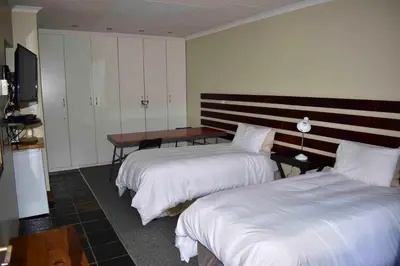 a hotel room with two beds and a table at 13 Hobson in Secunda