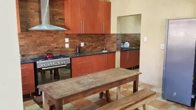 a kitchen with wooden cabinets and a bench in it at Hornbills Rest Country Home in Phalaborwa