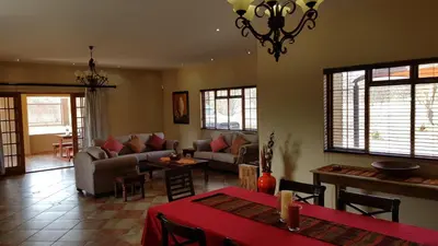 a living room with couches and a table and chairs at Hornbills Rest Country Home in Phalaborwa