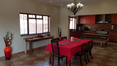 a dining room with a red table and chairs at Hornbills Rest Country Home in Phalaborwa