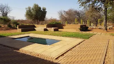 a swimming pool in the middle of a park at Hornbills Rest Country Home in Phalaborwa