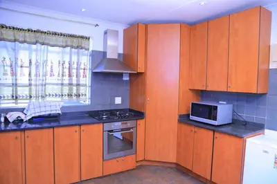 a kitchen with wooden cabinets and a microwave at Union Guesthouse in Pretoria