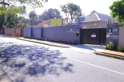 a street with a blue fence and a building at Union Guesthouse in Pretoria