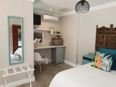 a bedroom with a bed and a desk and a mirror at NOOii Open Plan Room in Pretoria