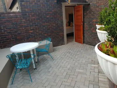 a patio with a table and chairs and a brick wall at NOOii Open Plan Room in Pretoria