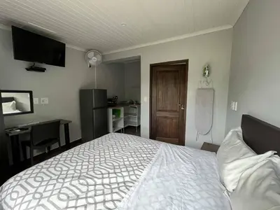 a bedroom with a bed and a desk and a television at Halleria Self Catering in White River
