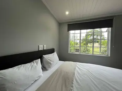 a bedroom with a white bed with a window at Halleria Self Catering in White River