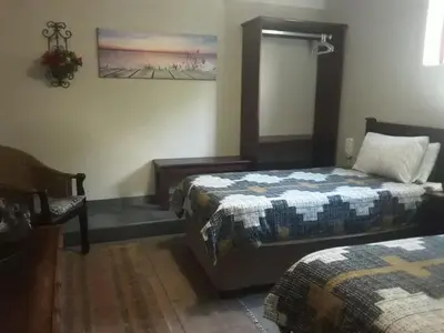 a bedroom with two beds and a chair in it at Meerkat Manor in Komatipoort