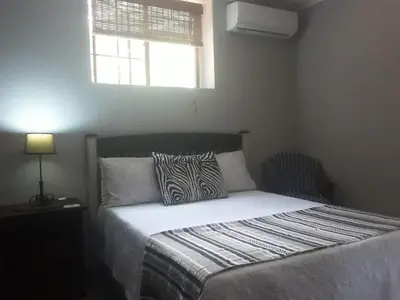 a bedroom with a bed with a zebra pillow and a window at Meerkat Manor in Komatipoort