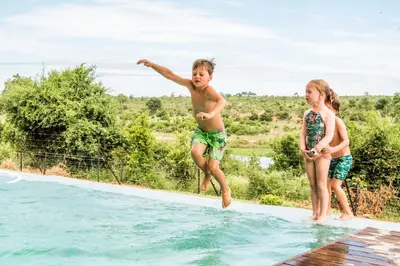 a boy and two girls jumping into a swimming pool at Jacana River Lodge Mjejane Game Reserve in Hectorspruit