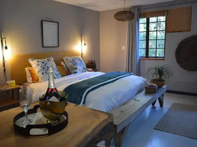 a bedroom with a bed and a table with a bottle of wine at Waterbessiebos cottage in Tzaneen