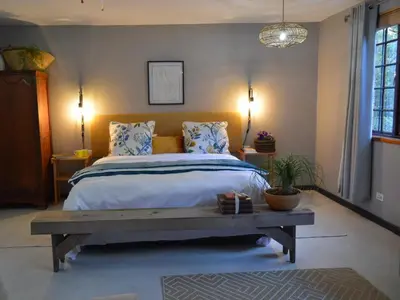 a bedroom with a large bed and a wooden bench at Waterbessiebos cottage in Tzaneen