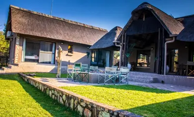 a house with a stone retaining wall next to a yard at Lindanda Luxury Lodge in Hoedspruit