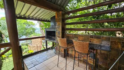 a screened in porch with a fireplace and chairs at Pont de Fleur in Hartbeespoort