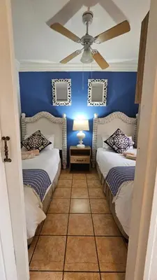 two beds in a blue room with a ceiling fan at Pont de Fleur in Hartbeespoort