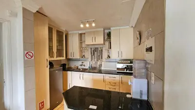a kitchen with wooden cabinets and a black counter top at Pont de Fleur in Hartbeespoort