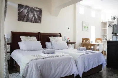 two beds in a room with white sheets at Panda's Guest Cottages in Kaapsehoop