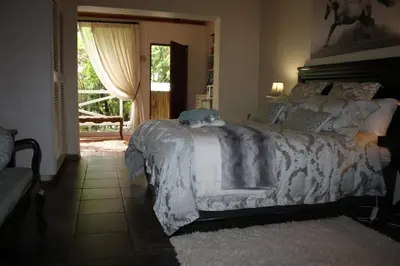 a bedroom with a bed with a white comforter at Panda's Guest Cottages in Kaapsehoop