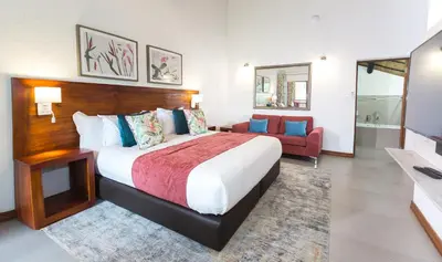 a bedroom with a large bed and a red chair at Kruger Park Lodge Unit No. 608B in Hazyview