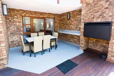 a patio with a table and chairs and a tv on a brick wall at Kruger Park Lodge Unit No. 610B in Hazyview