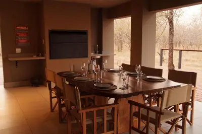a dining room with a large wooden table and chairs at Uchawi wa Afrika in Marloth Park