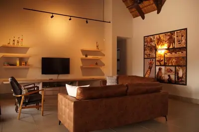 a living room with a brown couch and a tv at Uchawi wa Afrika in Marloth Park