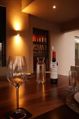 a bottle of wine and a wine glass on a table at Uchawi wa Afrika in Marloth Park