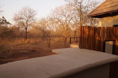 a porch of a house with a fence and trees at Uchawi wa Afrika in Marloth Park