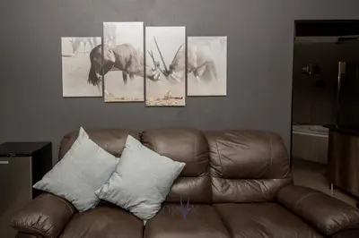 a group of elephant paintings on a wall above a couch at Oryx B&B Reserved Guests Only in Mokopane