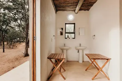 a bathroom with a sink and two wooden benches at Mopane Bush Lodge in Linton
