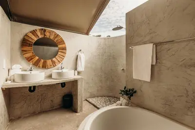 a bathroom with two sinks and a tub and a mirror at Mopane Bush Lodge in Linton
