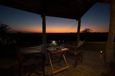 a table and chairs under a tent with a sunset at Mopane Bush Lodge in Linton