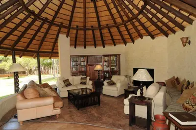 a living room with couches and a large ceiling at Mopane Bush Lodge in Linton