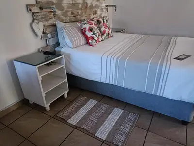 a bedroom with a bed with a nightstand next to it at King Protea Self Catering Accommodation in Erasmuskloof, Pretoria East in Pretoria