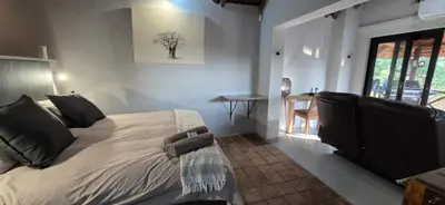a bedroom with a bed and a table and a window at The South Post @ Kruger in Marloth Park