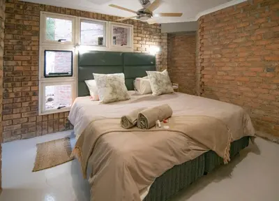 a bedroom with a large bed in a brick wall at The South Post @ Kruger in Marloth Park