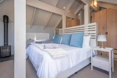 a bedroom with a large white bed with blue pillows at 109 Upwood in Dullstroom