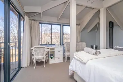 a bedroom with a bed and a desk and windows at 109 Upwood in Dullstroom