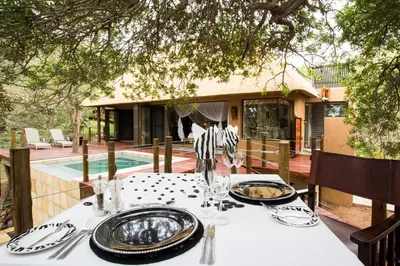 a table with plates and silverware on top of a table at Naledi Lodges in Balule Game Reserve