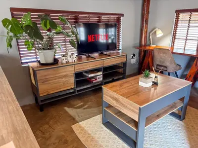 a living room with a tv on a wooden entertainment center at @30 Zebra in Polokwane