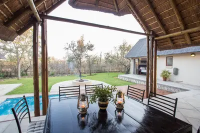 a patio with a table and chairs and a pool at Igugu Lodge in Hoedspruit