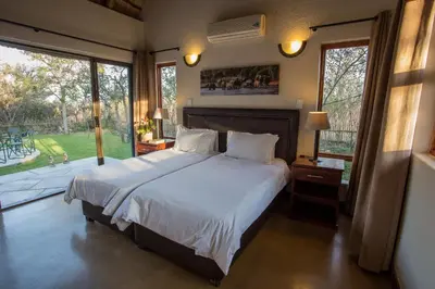 a bedroom with a large bed and a large window at Igugu Lodge in Hoedspruit