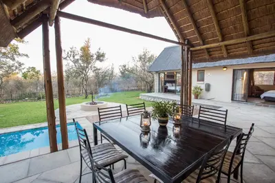 a patio with a table and chairs and a pool at Igugu Lodge in Hoedspruit