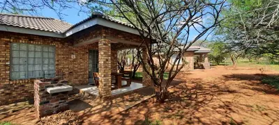 a brick house with a porch and a tree at 462 Bosbok Chalets in Marloth Park