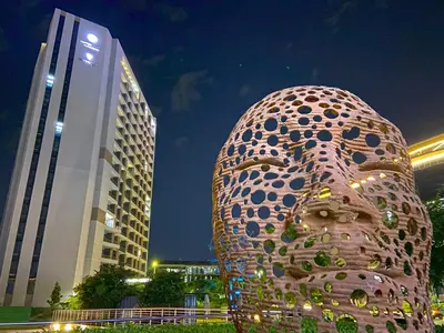 a giant donut statue in front of two buildings at Menlyn Maine Residences - Napoli with king sized bed in Pretoria