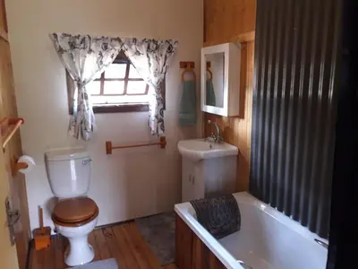 a bathroom with a toilet and a tub and a window at Declan House in Louis Trichardt