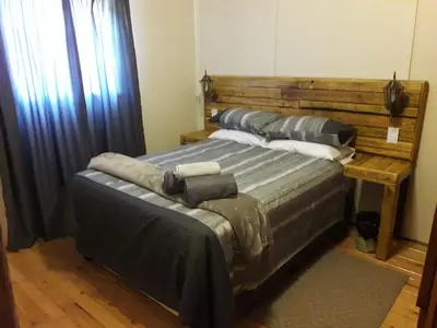 a bedroom with a large bed with a wooden headboard at Declan House in Louis Trichardt